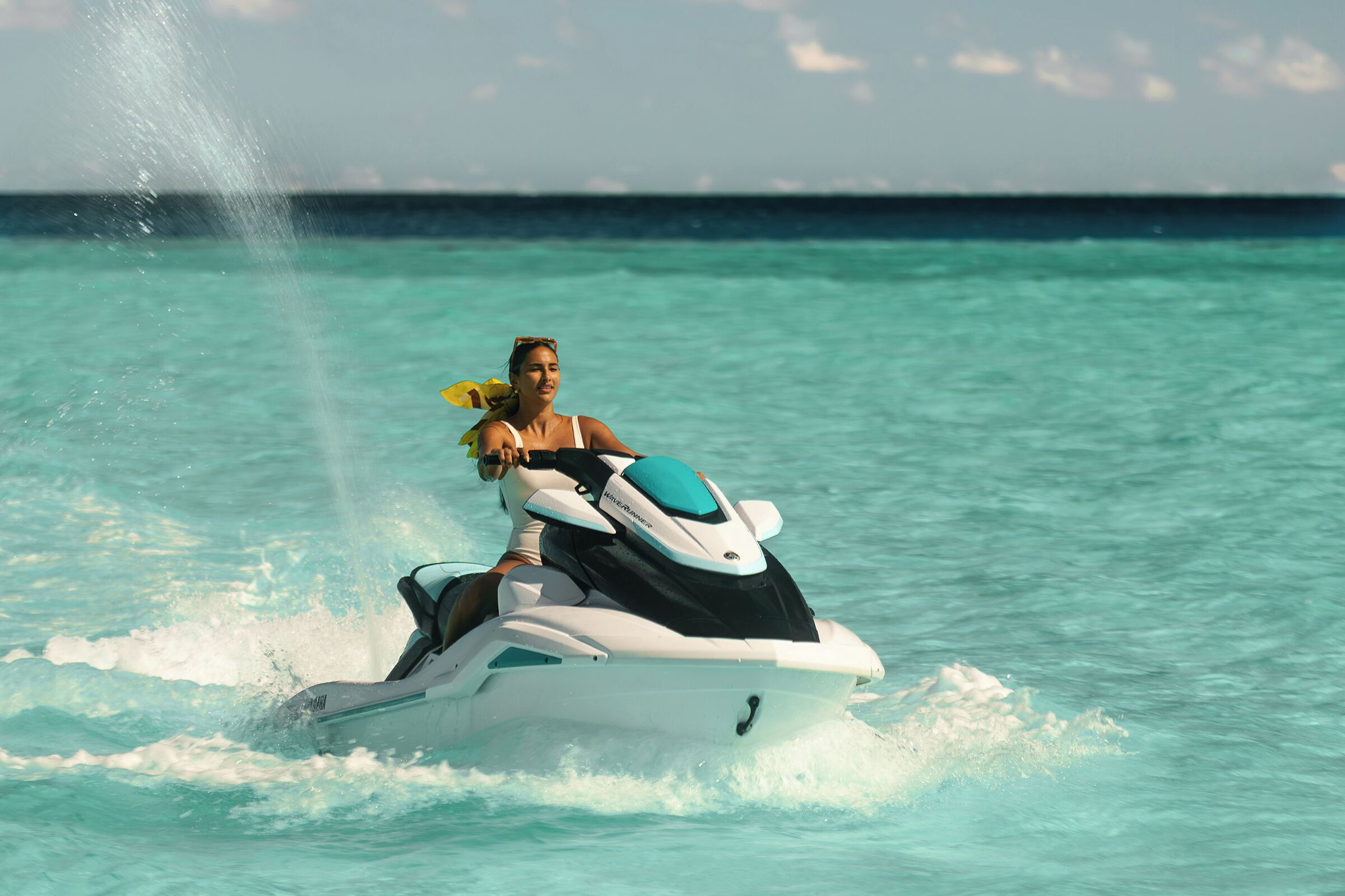Una persona conduciendo un jet ski sobre aguas turquesas.