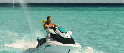 Una persona conduciendo un jet ski sobre aguas turquesas.
