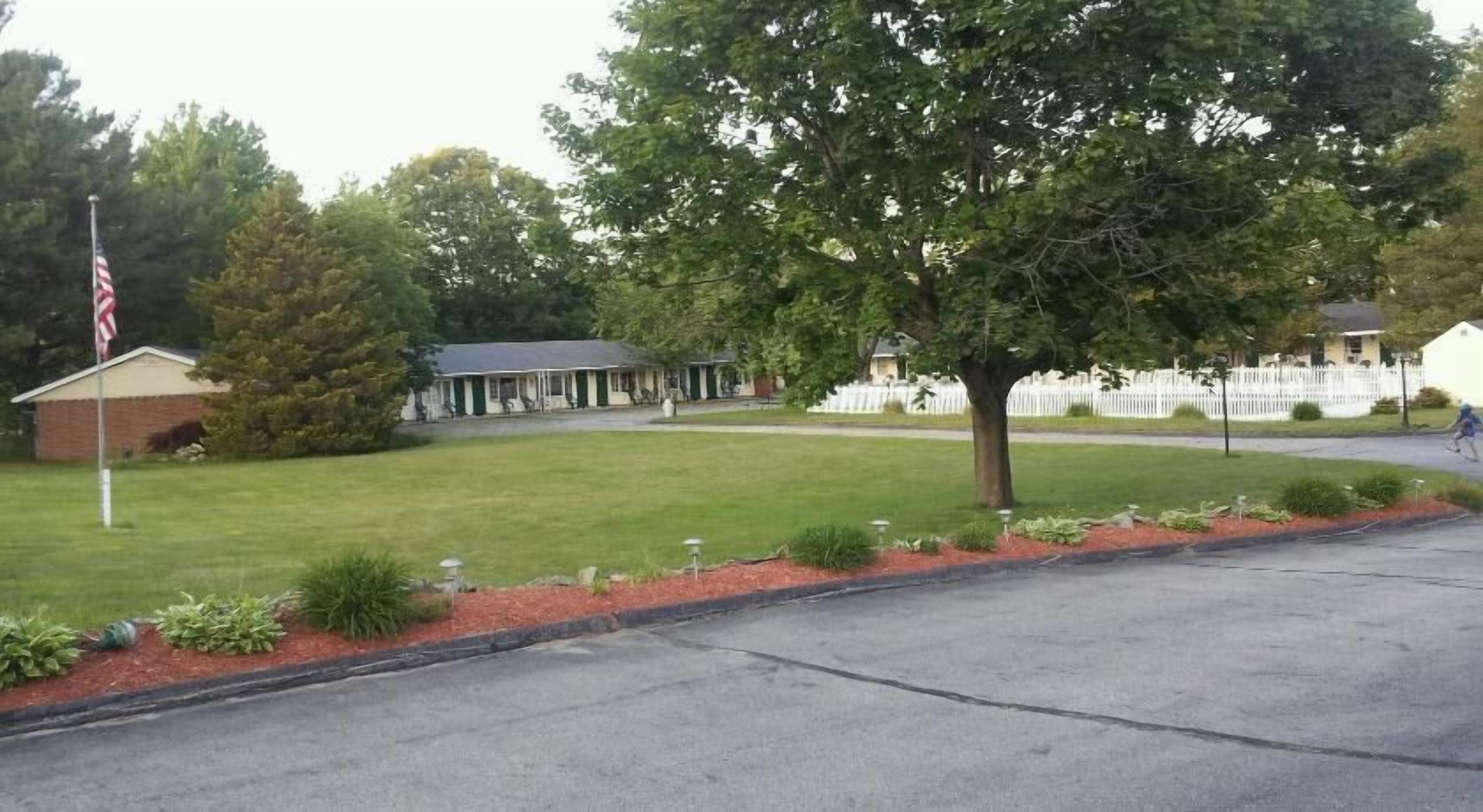 A residential area with a grassy lawn, a flag, and a building with a porch.