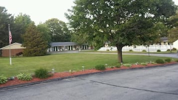 A residential area with a grassy lawn, a flag, and a building with a porch.