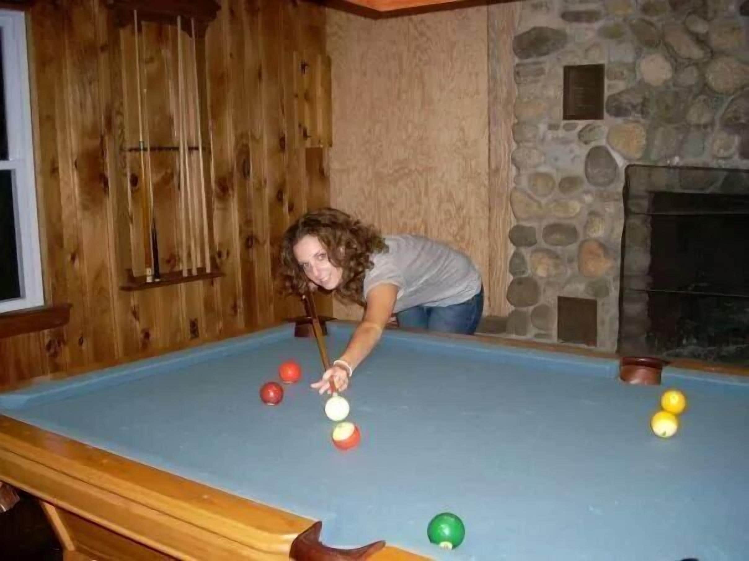 Une table de billard avec des billes et une personne penchée au-dessus.