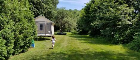 A grassy area with a small house and a trampoline.