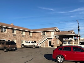 A two-story building with a covered parking area, a staircase leading to the upper floor, and a sign indicating an office.