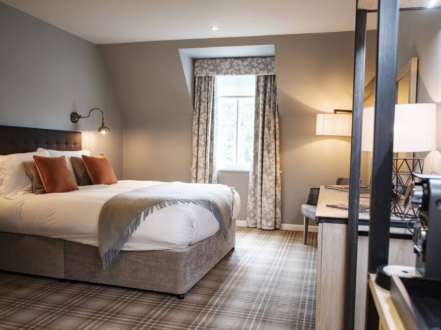Una habitación de hotel con cama, escritorio, silla y lámpara.