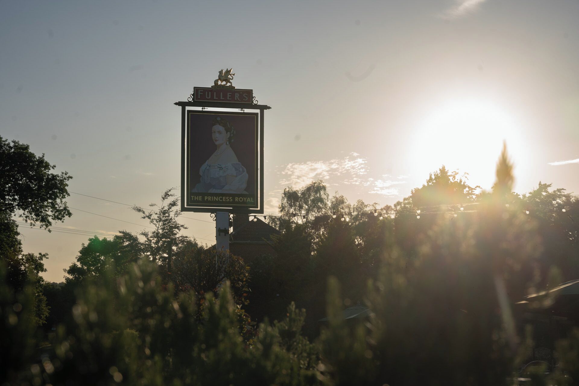 Et skilt med et portræt og tekst, omgivet af træer og en solnedgang.