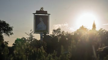 Et skilt med et portræt og tekst, omgivet af træer og en solnedgang.