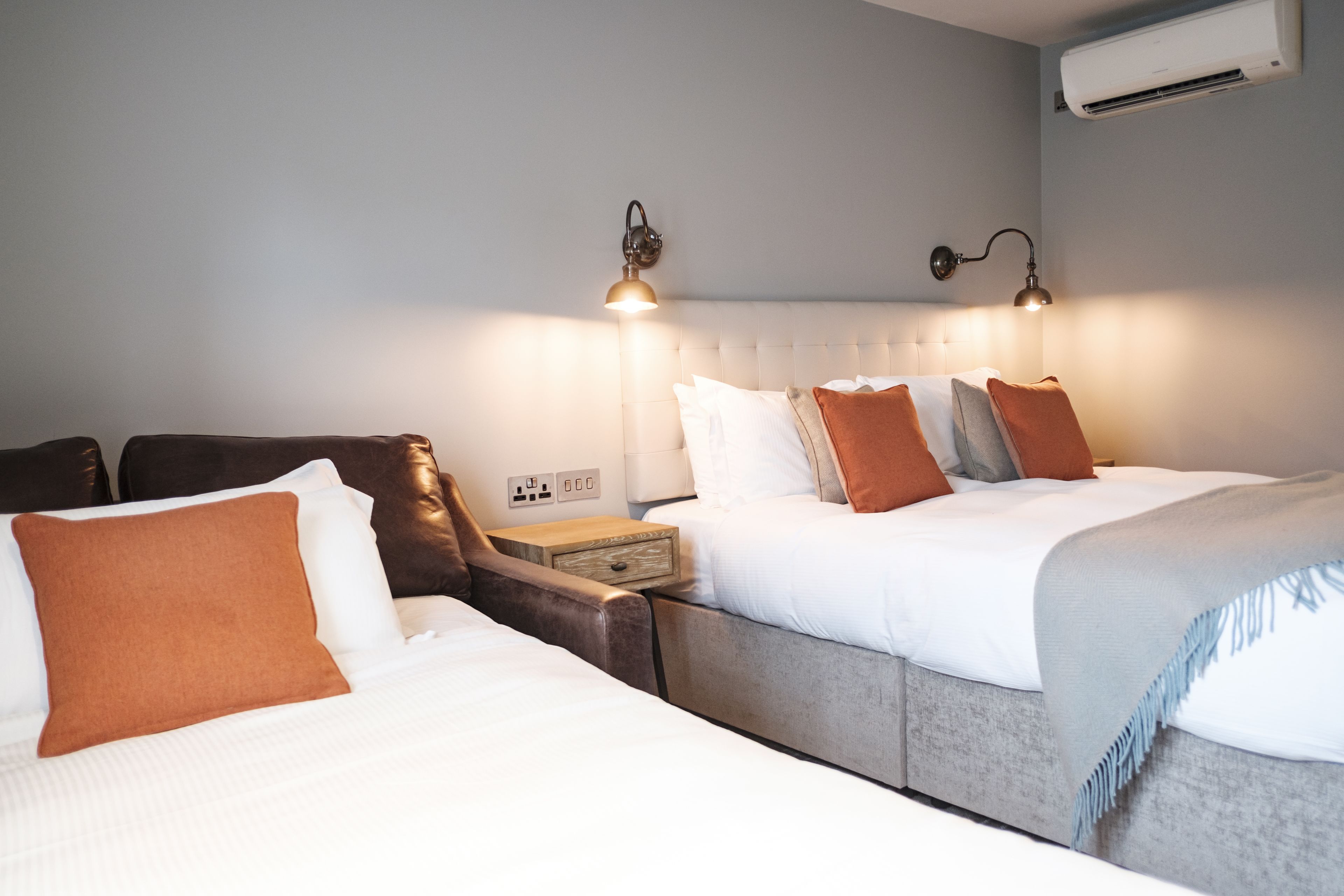 A hotel room with two beds, a nightstand, and wall-mounted lamps.