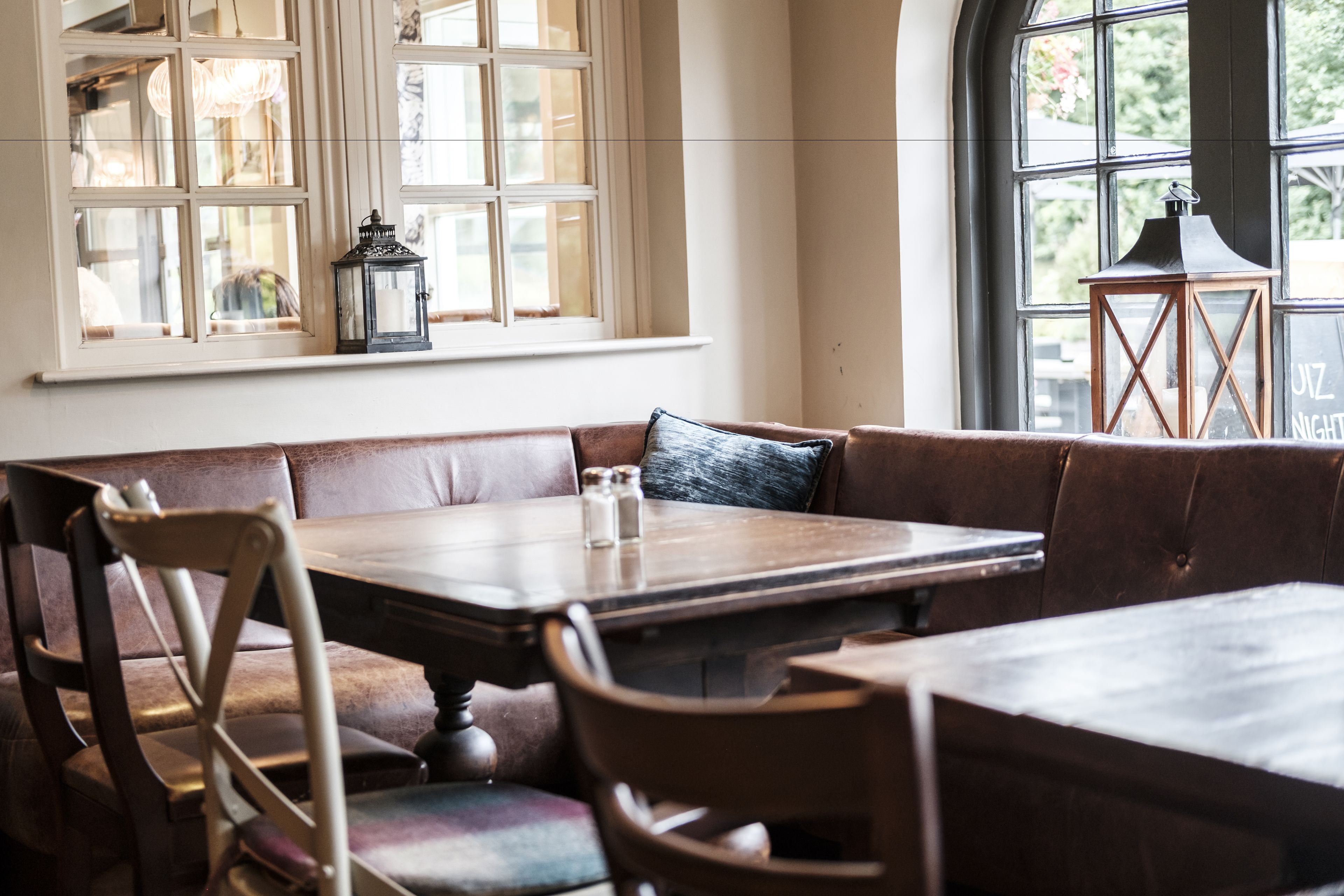 A cozy restaurant interior with a wooden table and cushioned seating.