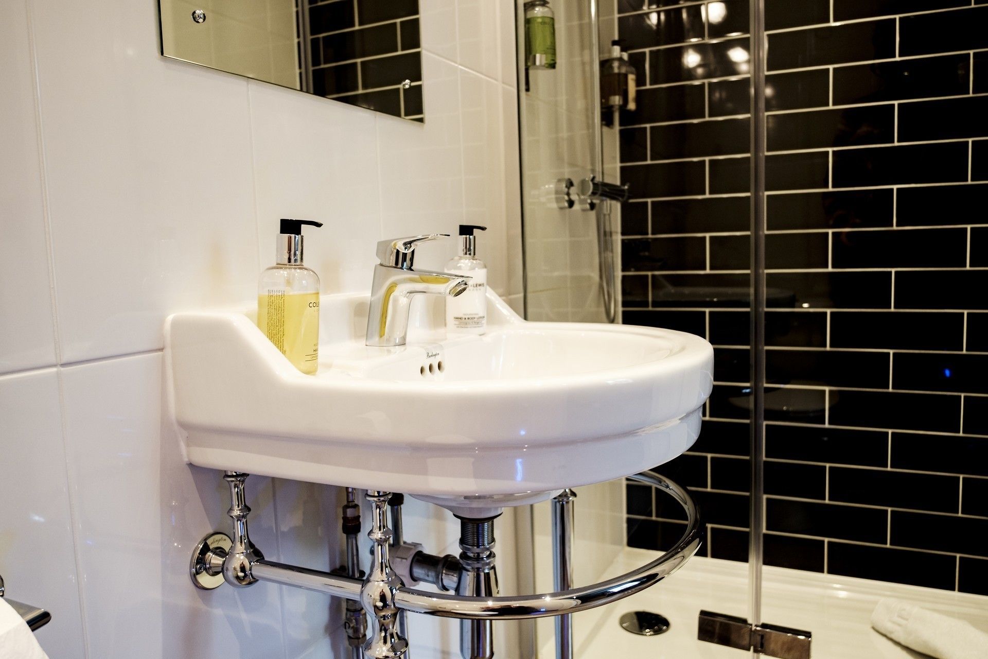 Ein Badezimmer mit einem weißen Waschbecken, zwei Seifenflaschen und einem Chromarmaturenset.