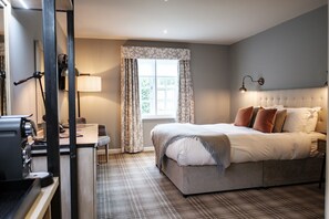 A bedroom with a bed, a desk, and a window with curtains.