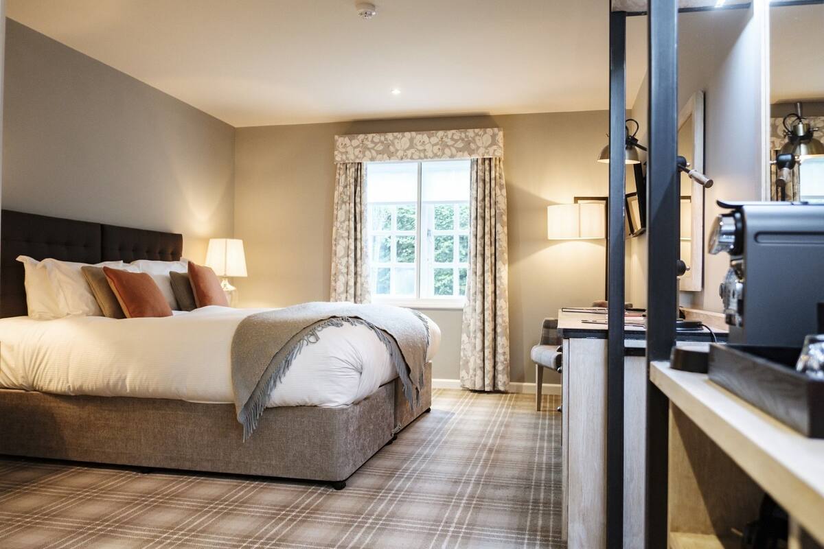 Ein Hotelzimmer mit einem Bett, einem Schreibtisch, einem Stuhl und einem Fenster mit Vorhängen.