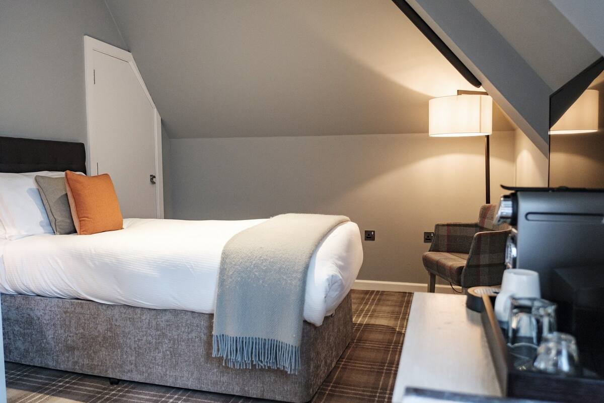 Ein Hotelzimmer mit Bett, Schreibtisch, Stuhl und Lampe.