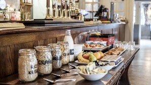 A buffet table with various food items and condiments, including jars of granola and a bottle of milk. - The Princess Royal (Farnham)