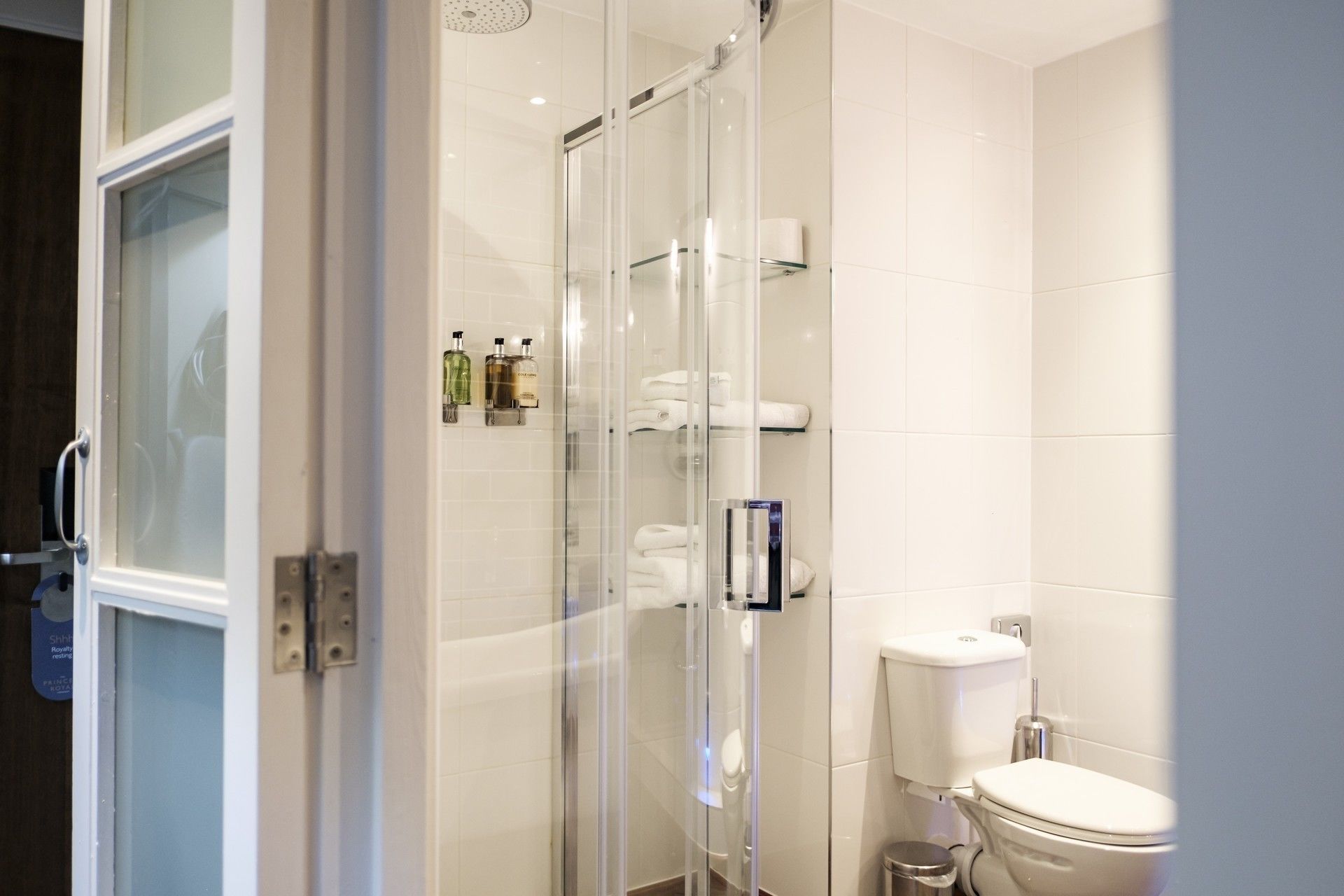 A modern bathroom with a glass shower enclosure, a toilet, and a glass door.