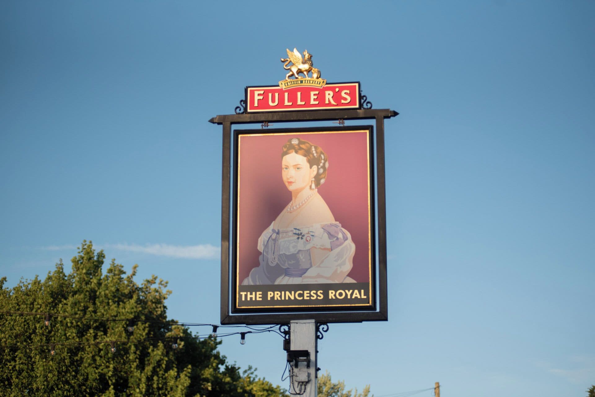 A sign with "FULLER'S" and "THE PRINCESS ROYAL" text, featuring a portrait of a woman in a dress.