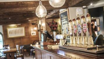 Een bar met houten lambrisering, een toonbank met biertappunten en hangende lampen.