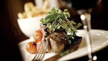 A plate with a steak, cherry tomatoes, and a garnish of greens.