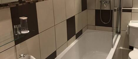 A bathroom with a bathtub, two sinks, a shower, and a toilet.