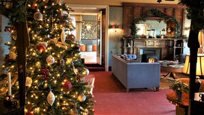 A cozy living room with a large Christmas tree, a fireplace, and a comfortable seating area. - Ravenstone Manor (Keswick)
