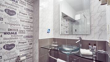 A modern bathroom with a glass sink, a large mirror, and a wall decorated with city names.