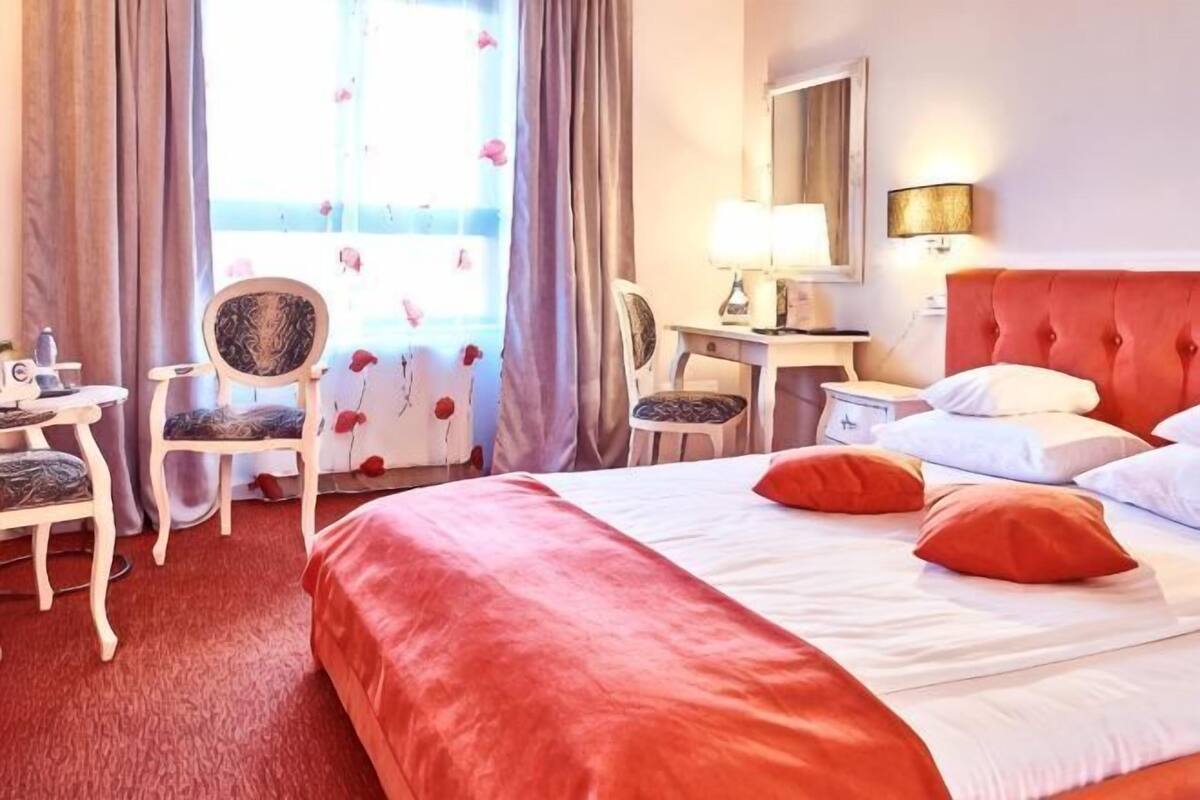 Ein Hotelzimmer mit einem Bett, zwei Stühlen, einem Schreibtisch und einer Lampe.