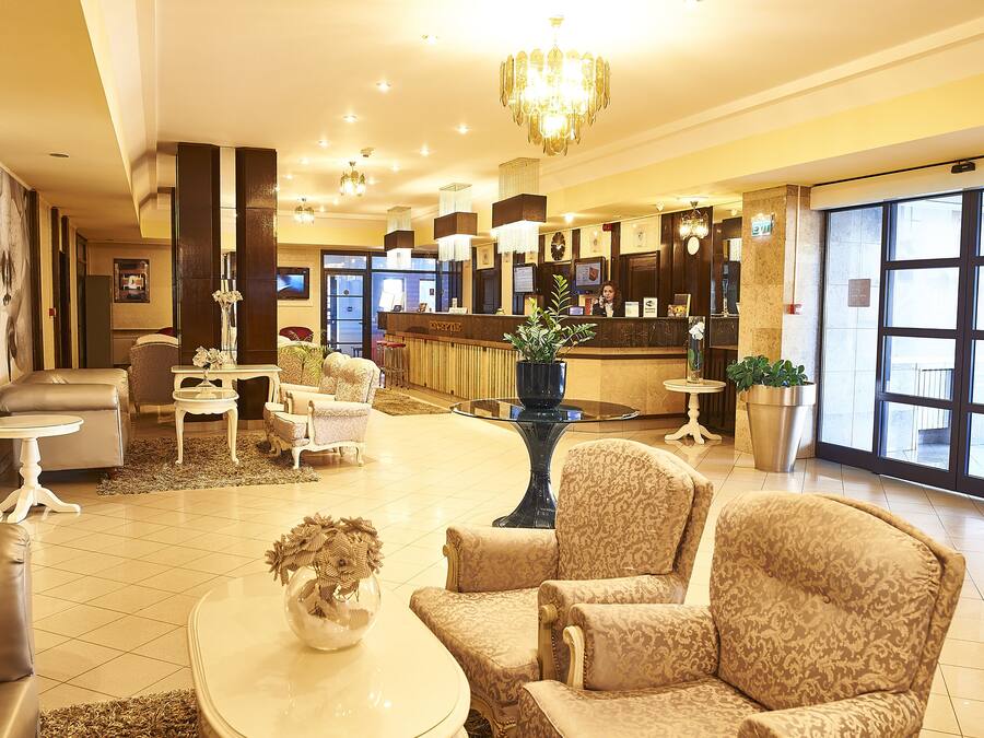 A hotel lobby with a reception desk, seating area, and a large window.