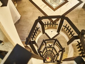 A spiral staircase with a geometric patterned floor and a metal railing. - Continental Forum Tirgu Mures (Targu Mures)