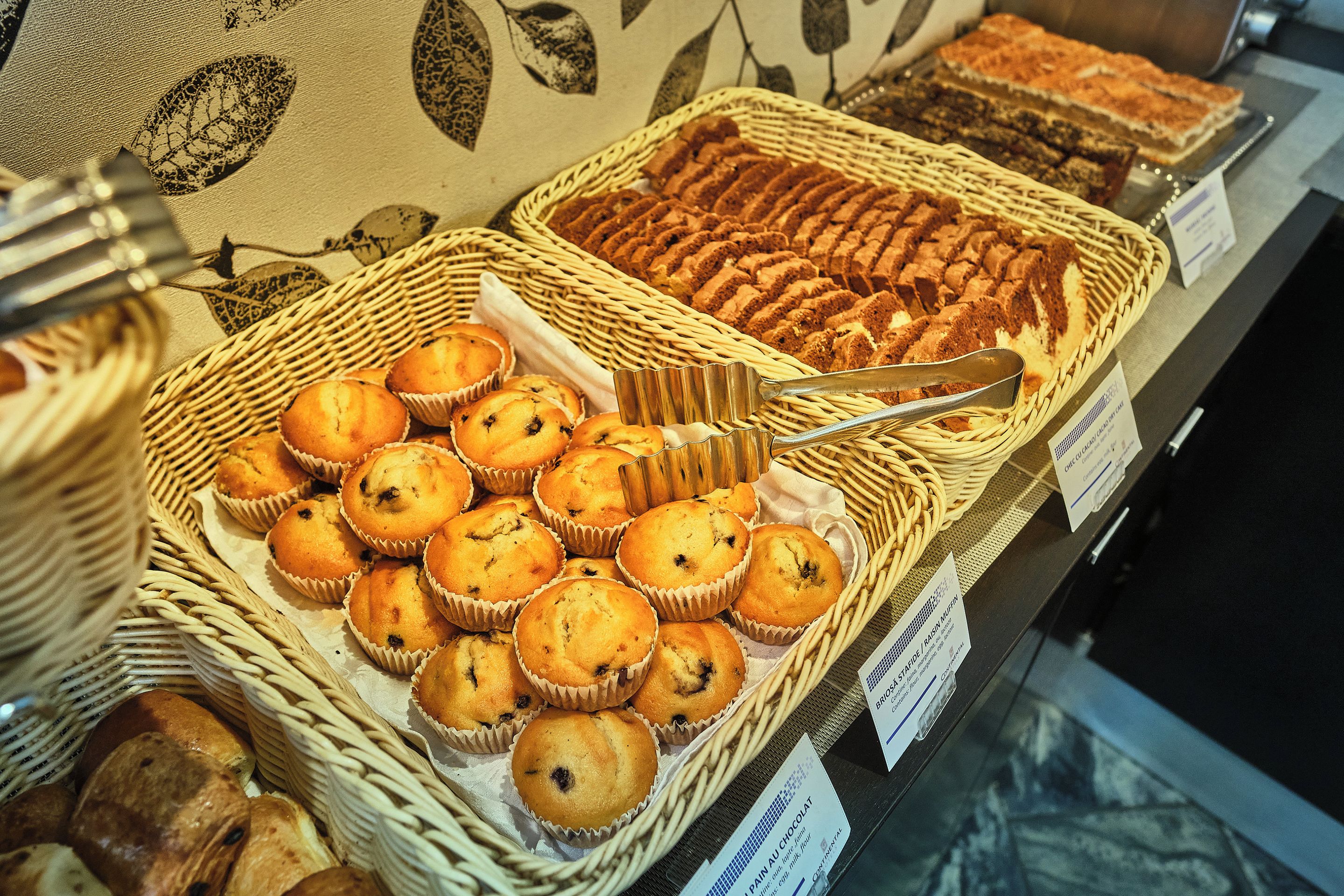 Un bancone di pasticceria con muffin e una torta.