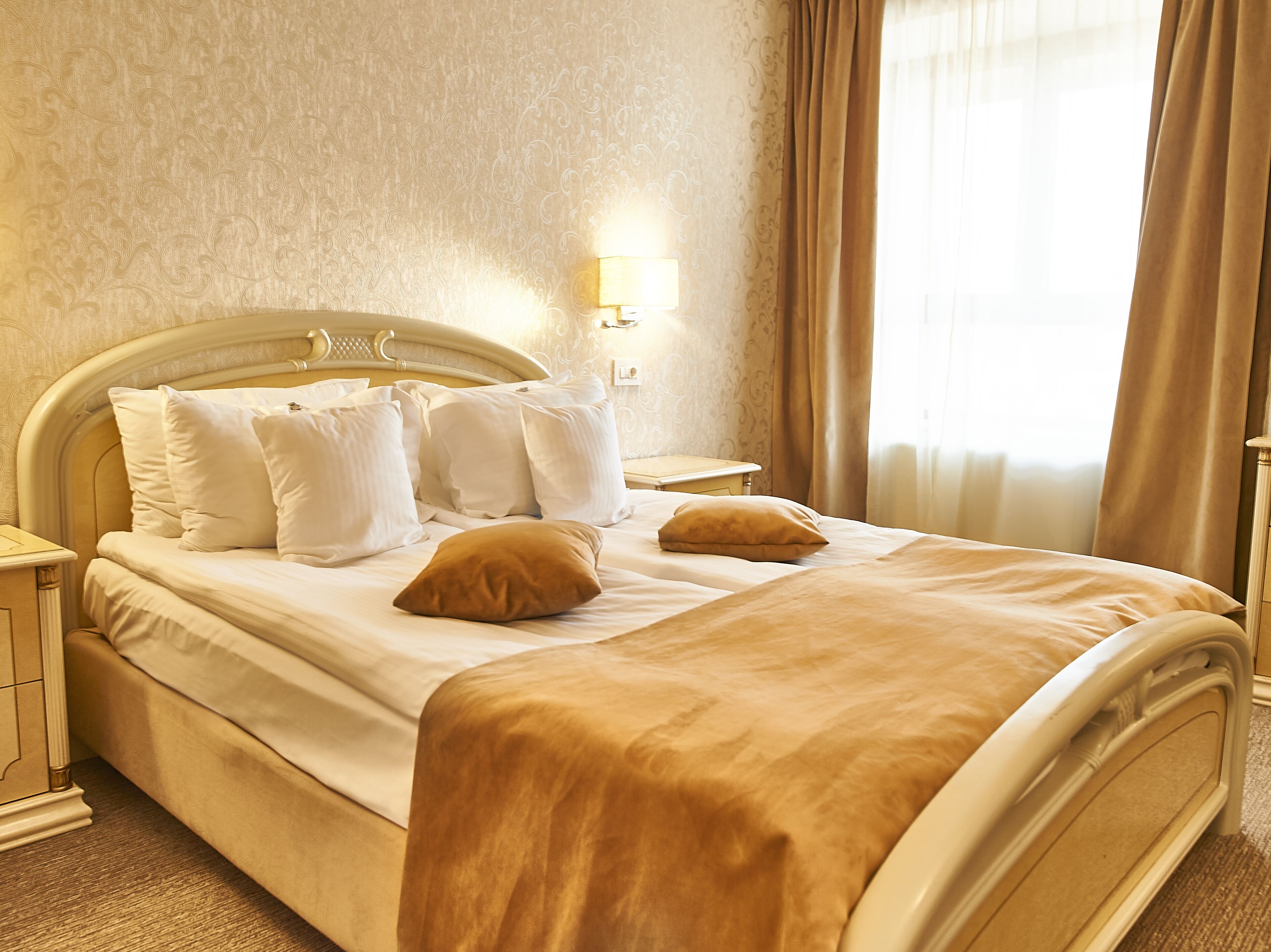 A neatly made bed with white and brown bedding, a bedside lamp, and a nightstand.
