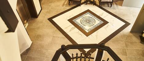 Un vestíbulo de hotel con suelo de diseño de mármol, una recepción y dos sillones.