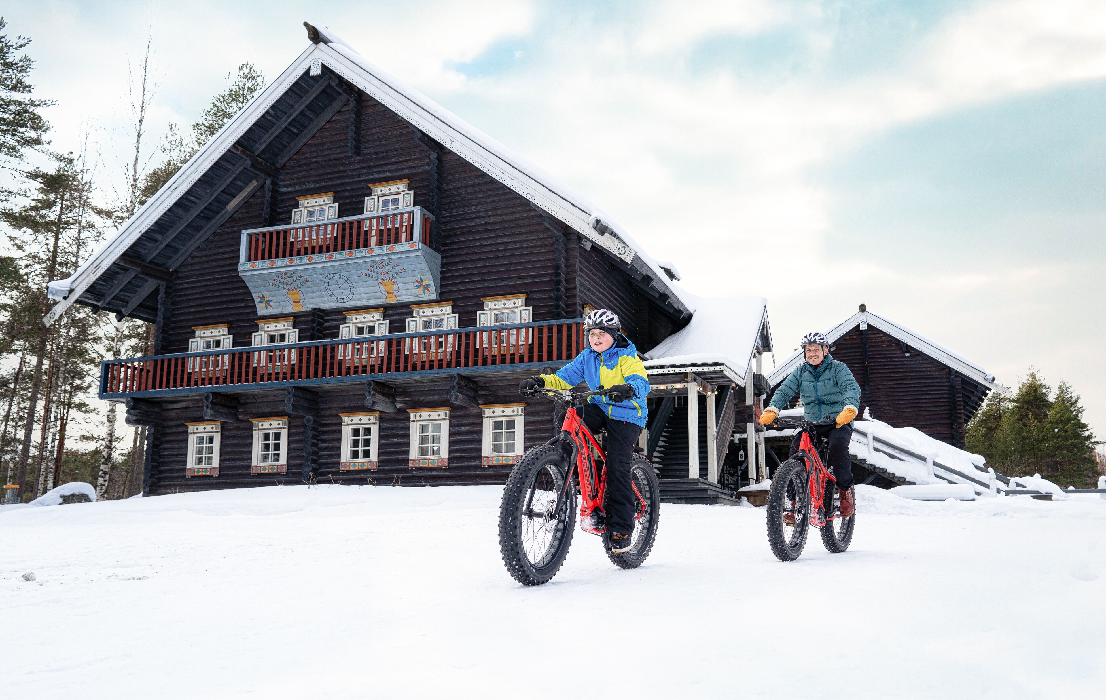 Una cabaña de madera con balcón, una escalera y un techo cubierto de nieve.