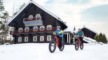 Una cabaña de madera con balcón, una escalera y un techo cubierto de nieve.