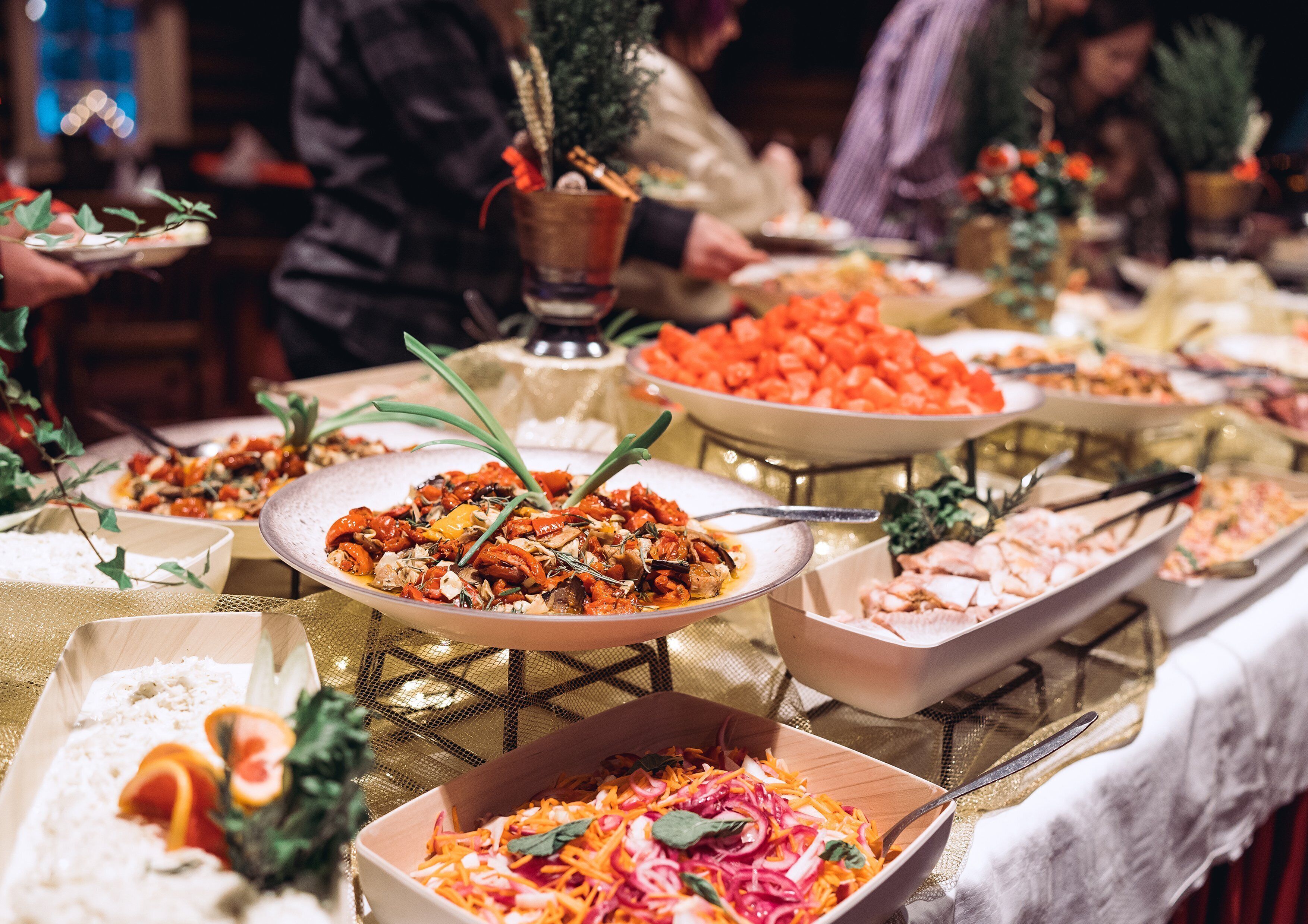 Une table de buffet proposant divers plats, notamment des salades, de la viande et des légumes.