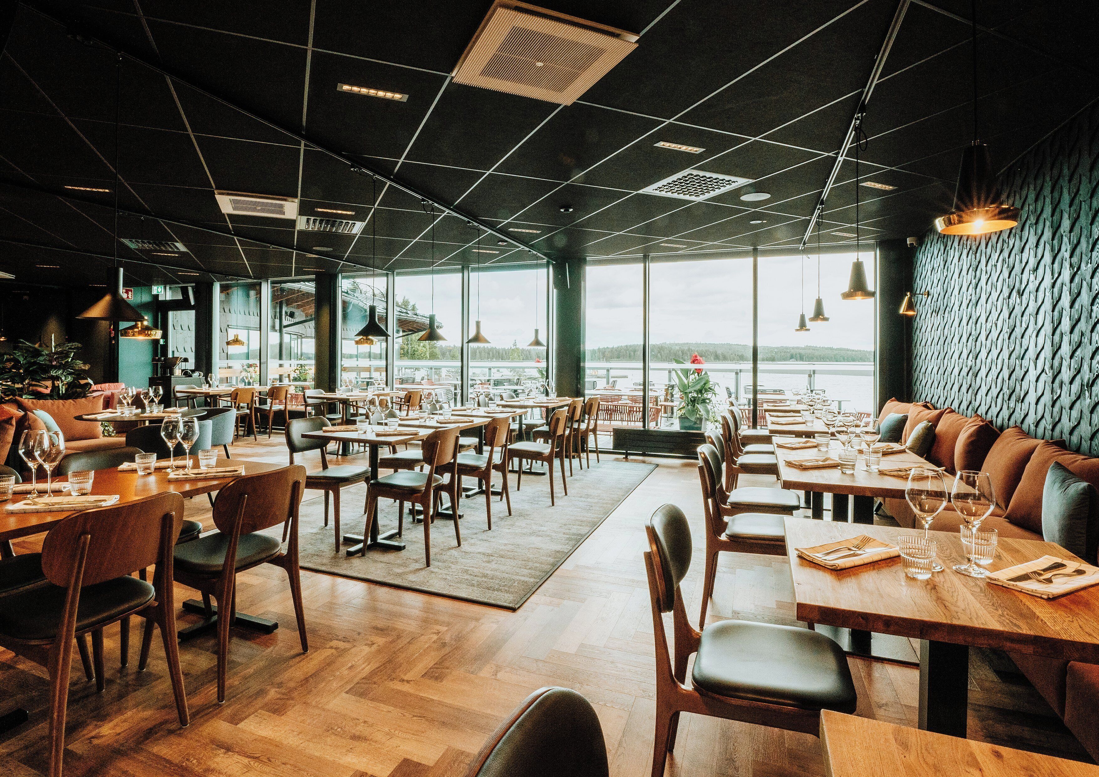 Un restaurant spacieux avec de hauts plafonds, de grandes fenêtres et une vue sur l’extérieur.