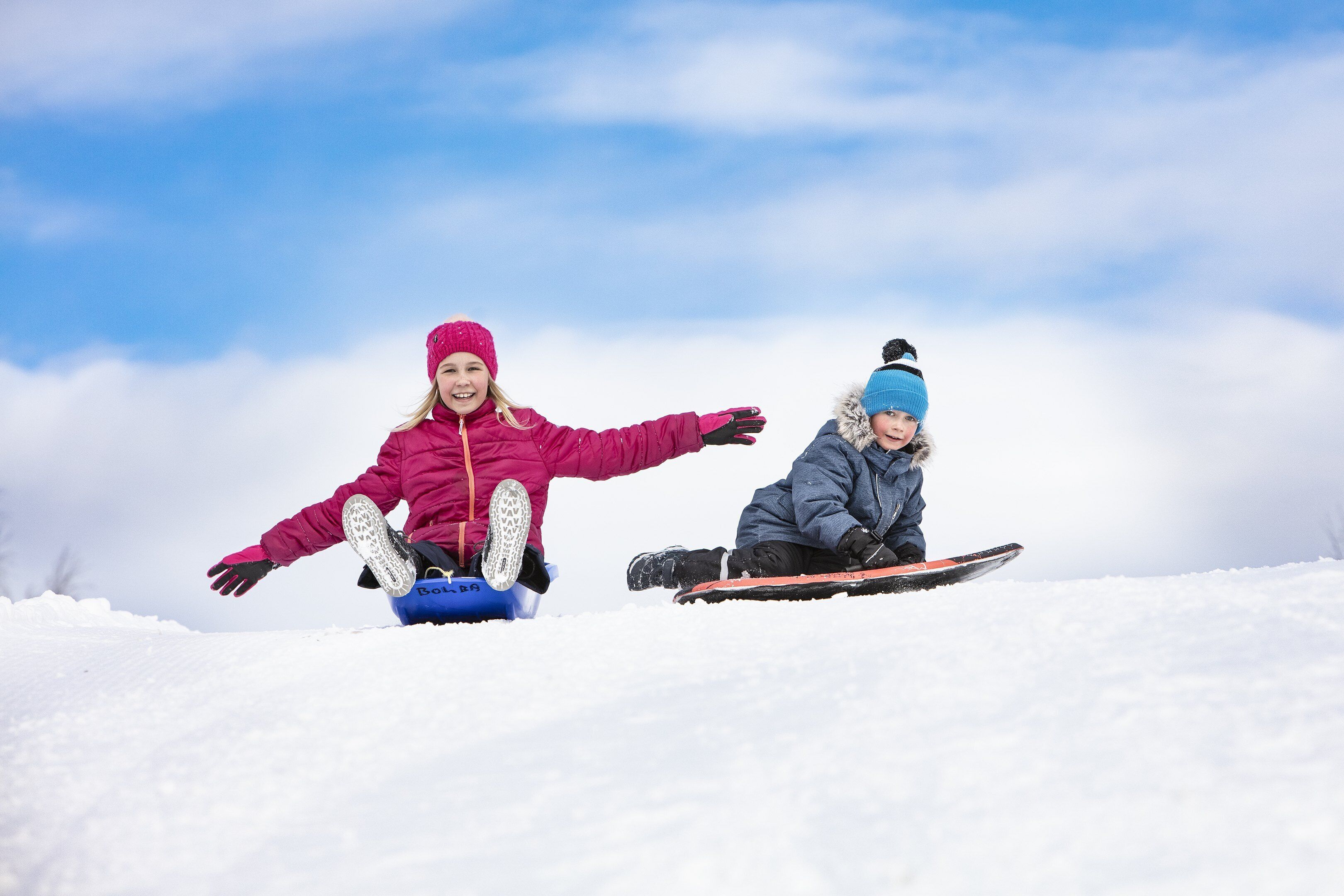 Dos niños esquiando sobre nieve en una ladera con cielo despejado al fondo.