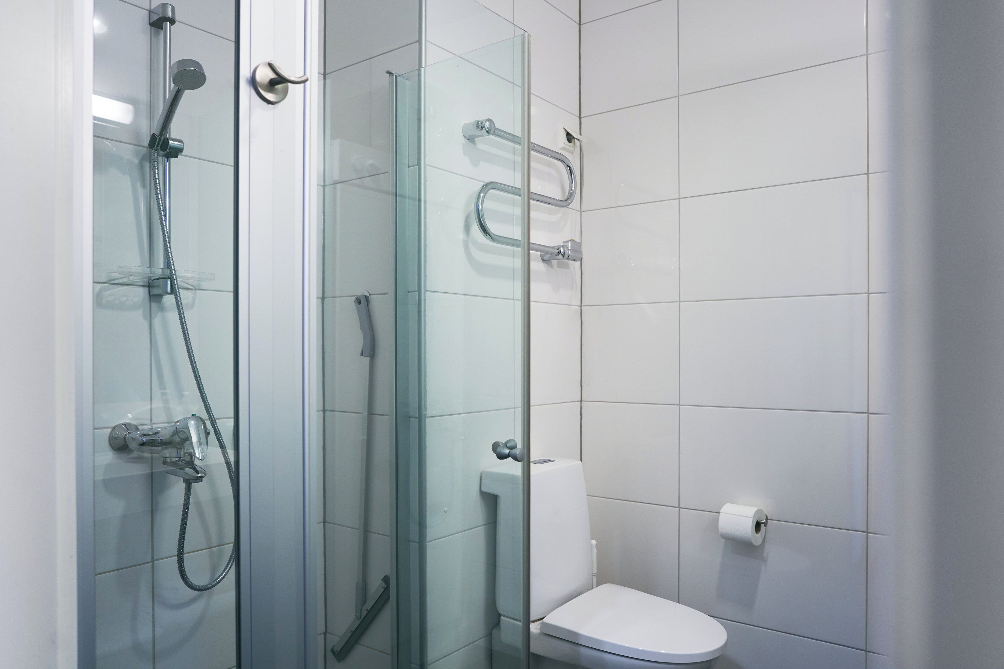 A modern bathroom with a glass-enclosed shower, a toilet, and a glass partition.