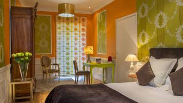 A hotel room with a bed, a desk, a chair, and a lamp.