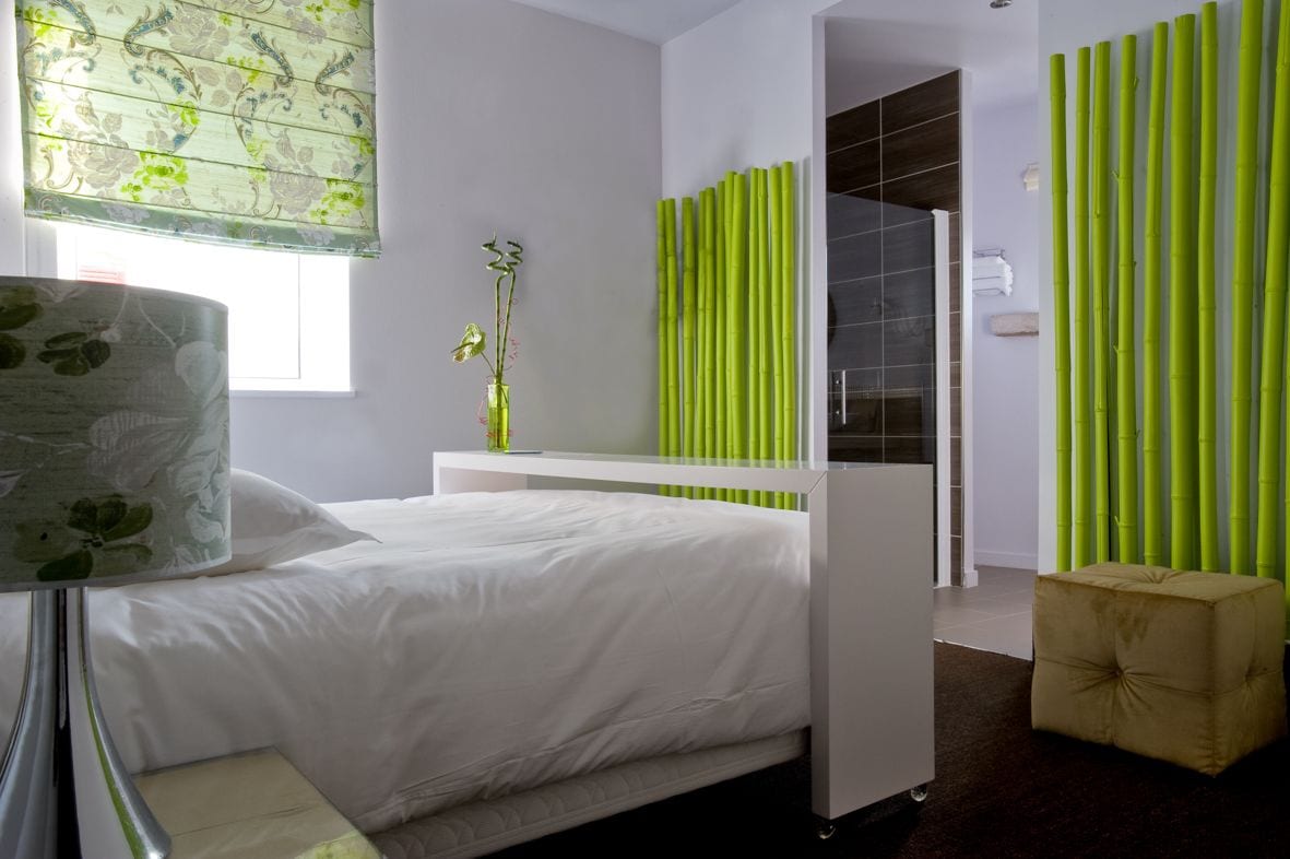 Un dormitorio moderno con cama, mesita de noche y espejo.