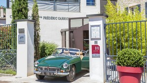 A green convertible car parked in front of a building with a sign reading "HOTEL & PREFERENCE". - Carrion Cuisine Hôtel & Spa (Vire)