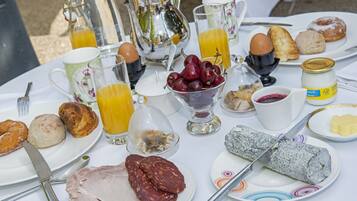 Una mesa de desayuno con diversos alimentos y bebidas, entre ellos huevos, pasteles y una botella de jugo.