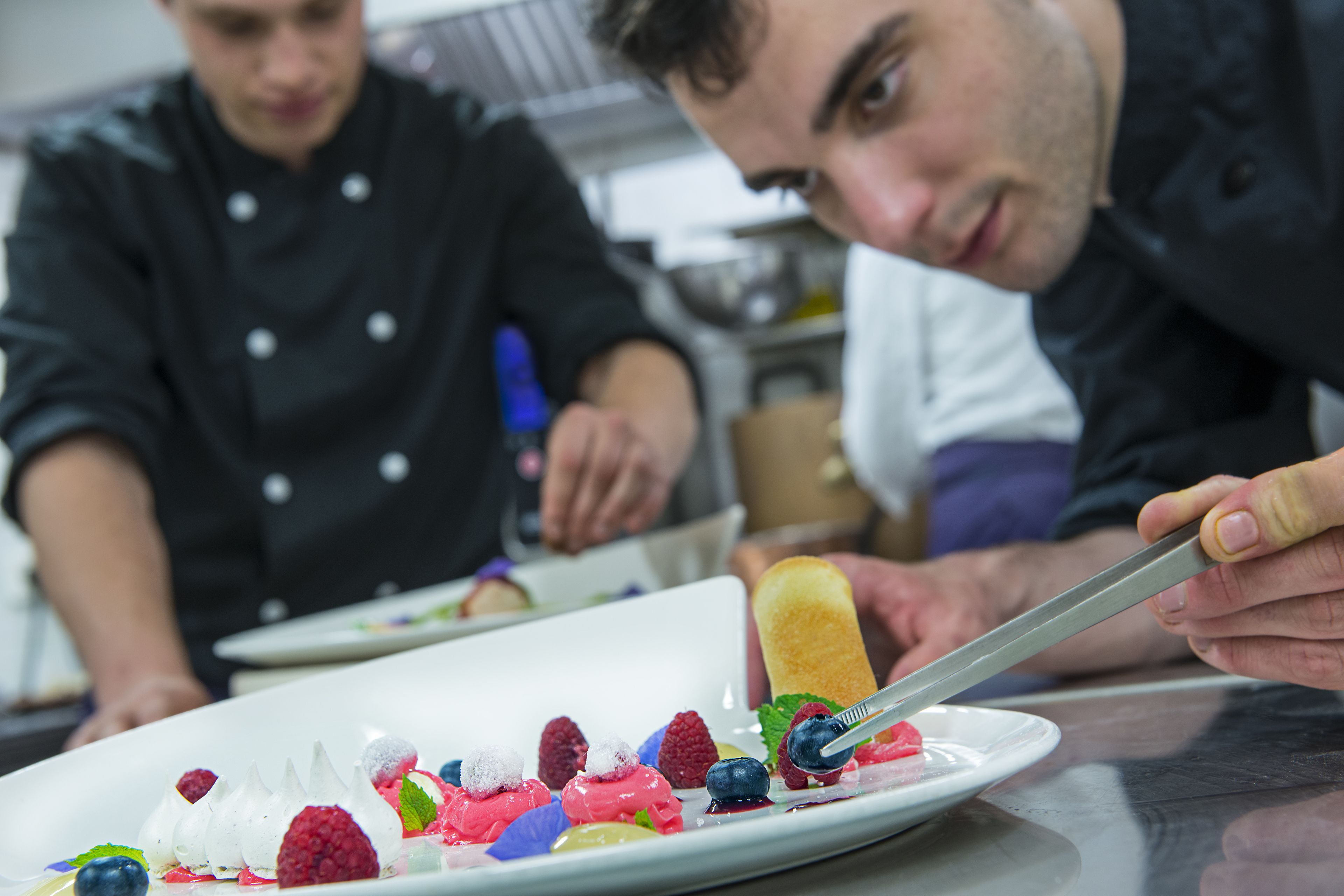 A chef preparing a dessert with various fruits and a knife.