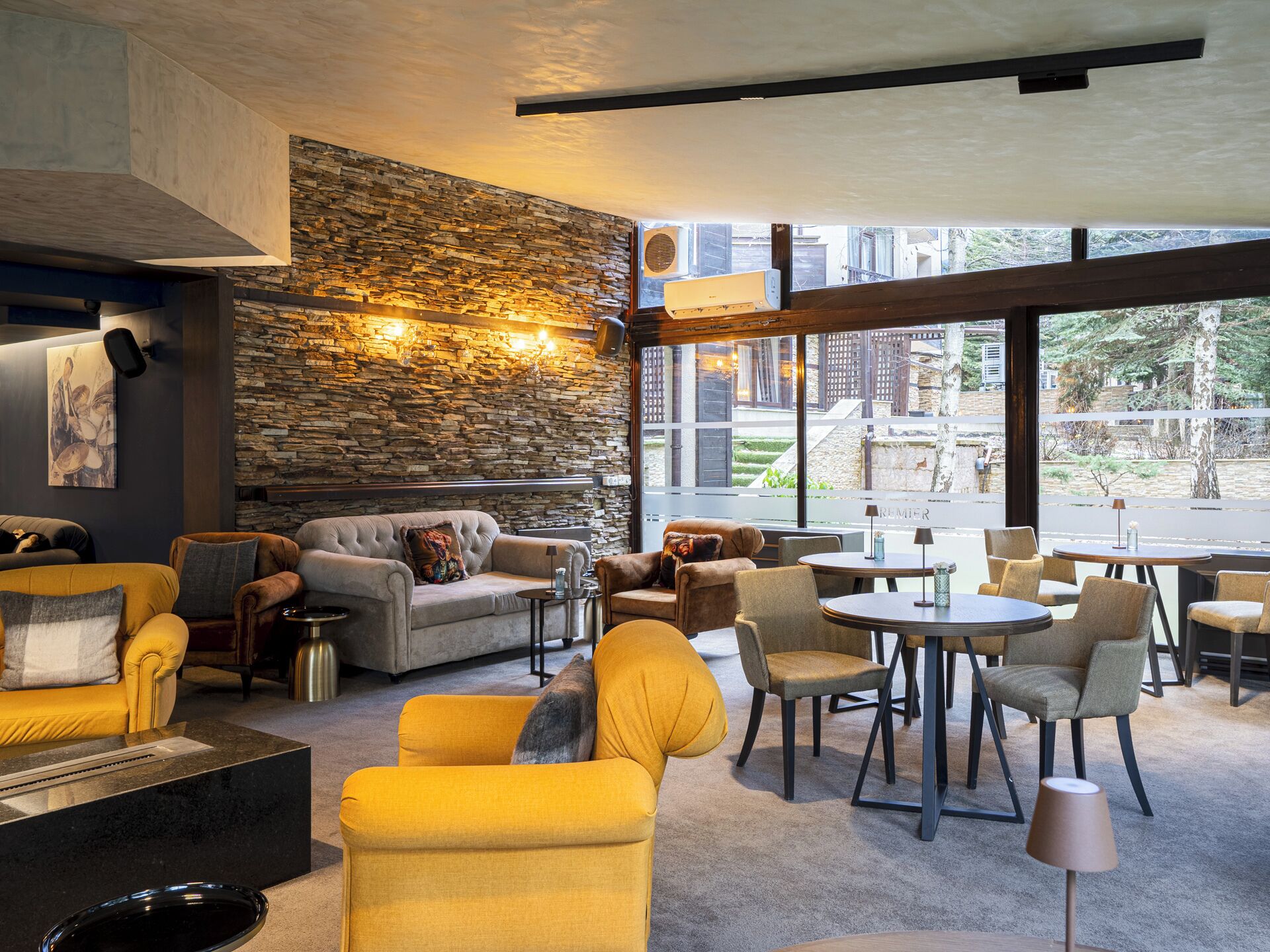 A modern interior with stone walls, comfortable seating, and large windows.