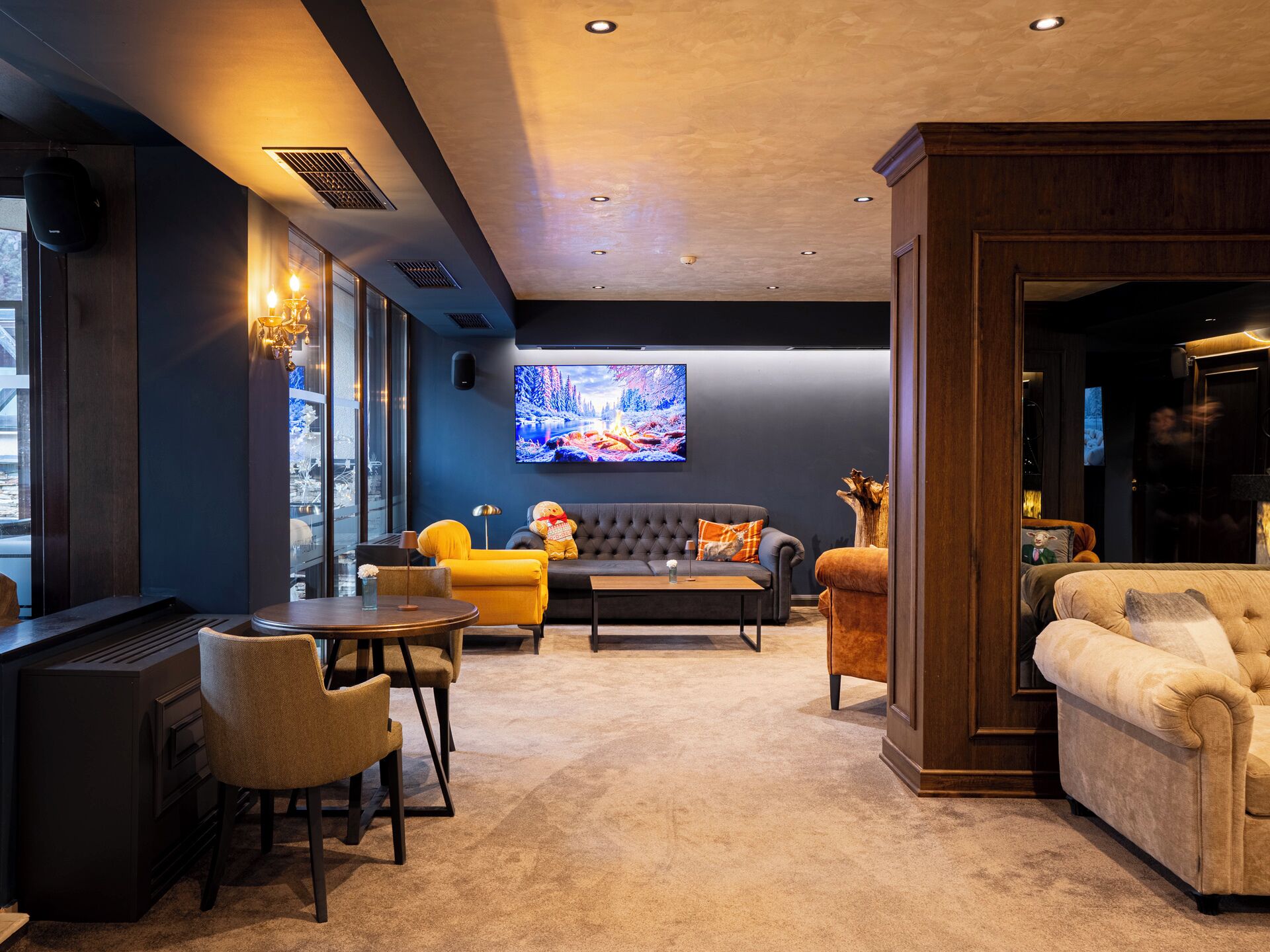 A modern living room with a large TV, comfortable seating, and a view of the outdoors.
