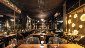 A restaurant with multiple tables, chairs, and a chandelier.