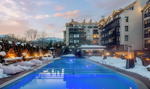 A hotel with a swimming pool surrounded by snow, featuring modern architecture and a mountain backdrop. - Premier Luxury Mountain Resort (Bansko)