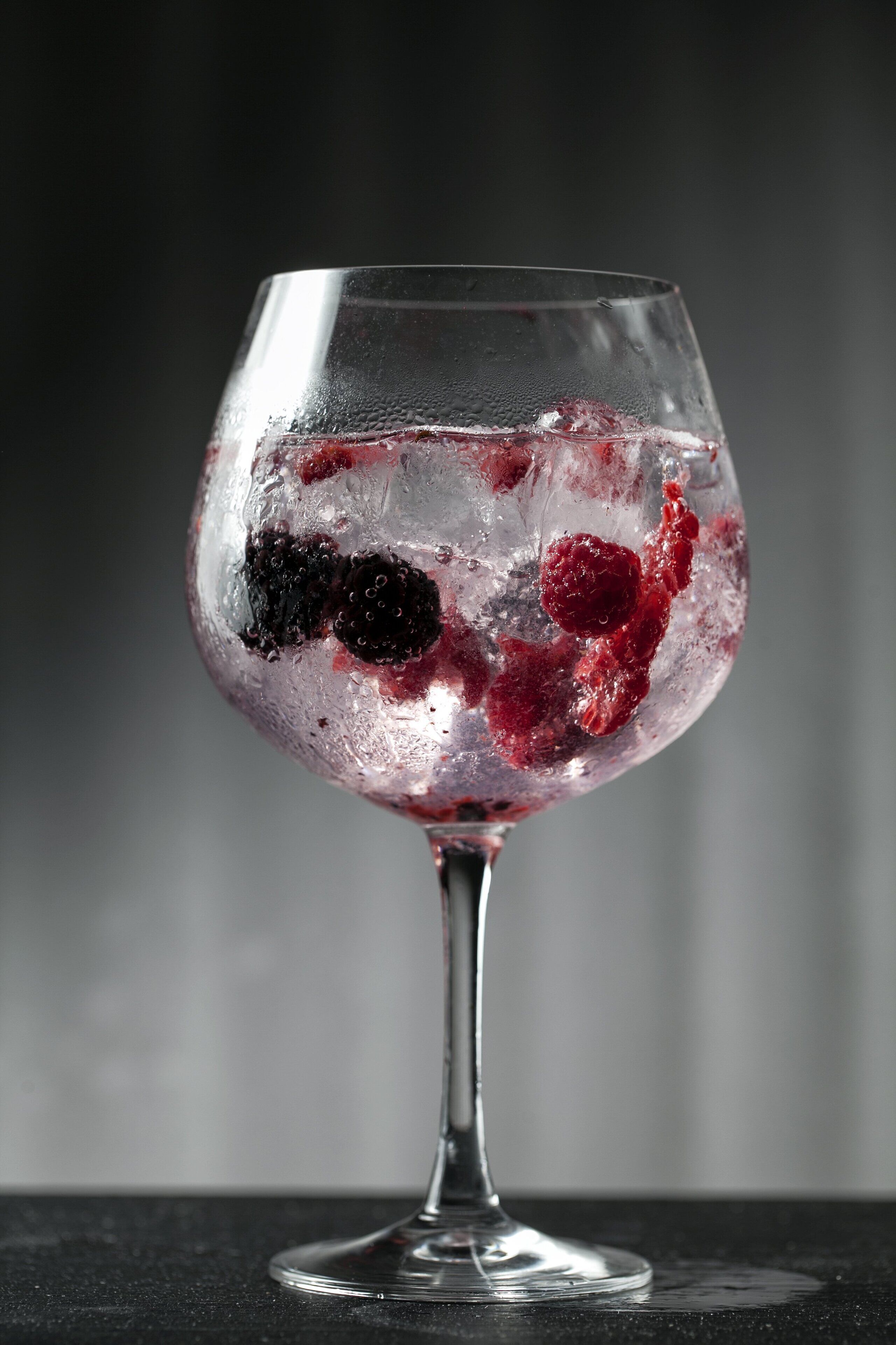 A clear glass with ice and berries.