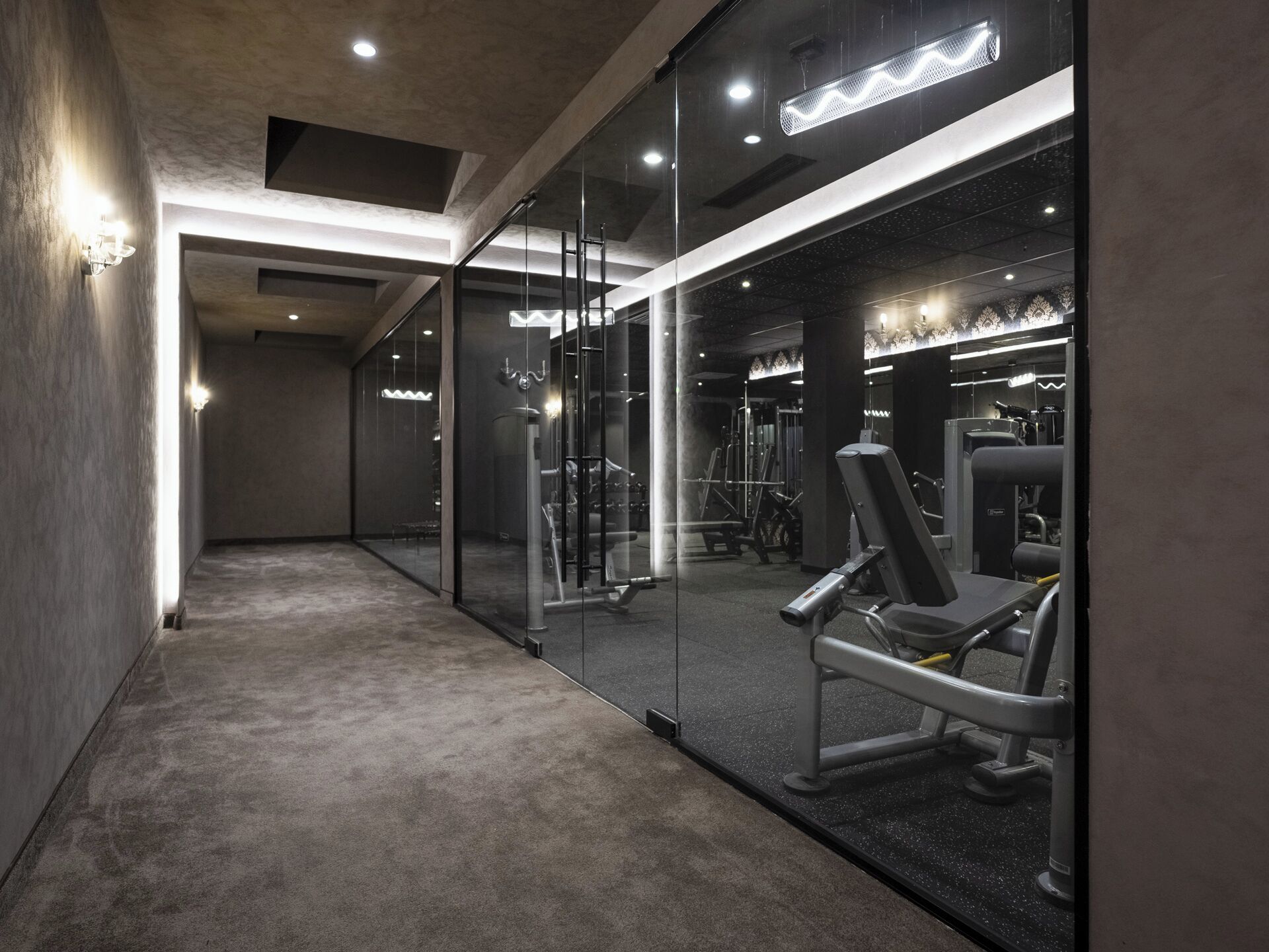 A gym with mirrored walls, exercise equipment, and a carpeted floor.