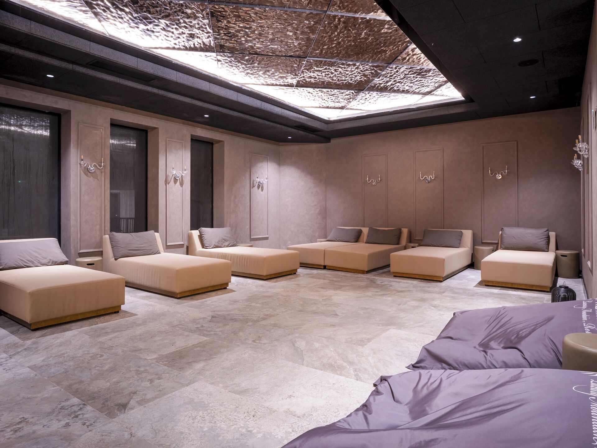 Una habitación de hotel moderna con tragaluz, varias camas y un espejo grande.