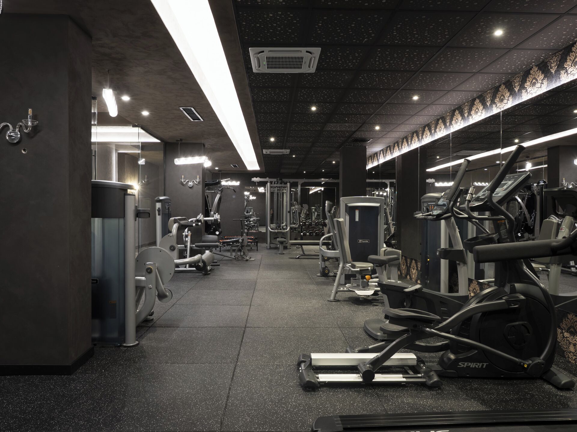 A modern gym with various exercise equipment, including treadmills and weight machines, under bright overhead lighting.