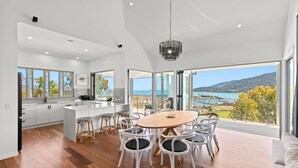 A modern kitchen with white cabinets, a wooden dining table, and white chairs.